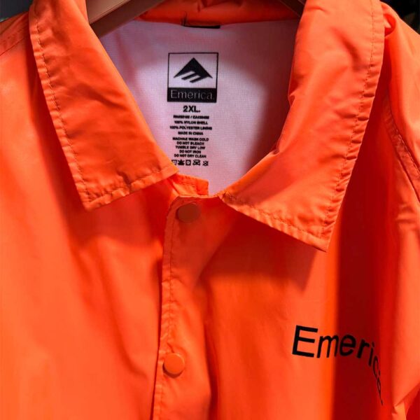 Emerica Coach Jacket σε έντονο φλούο πορτοκαλί χρώμα, με κουμπιά μπροστά και κλασικό γιακά, ιδανικό για άνοιξη και φθινόπωρο.
